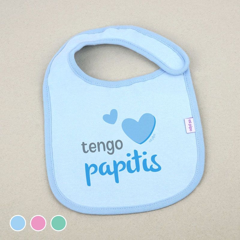 Babero azul claro con borde celeste y texto "tengo papitis" con dos corazones azules, cierre de velcro.