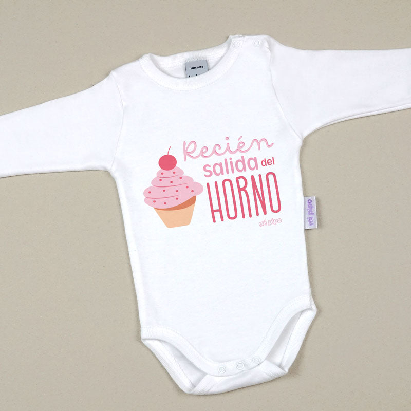 Body blanco de manga larga con estampado de cupcake rosa y texto "Recién salida del horno" en rosa y rojo.
