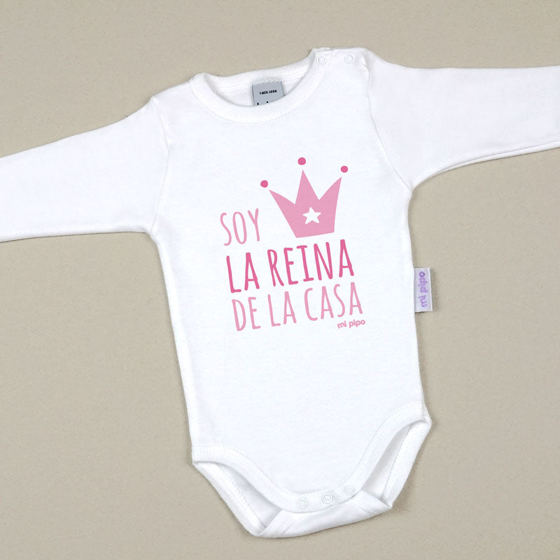 Body blanco de algodón para bebé con manga larga y texto rosa "Soy la reina de la casa" junto a una corona rosa.