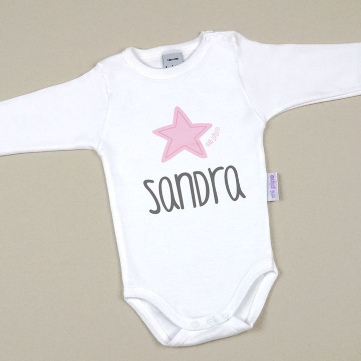 Body blanco para bebé con estrella rosa y nombre "Sandra" en letras grises, manga larga.
