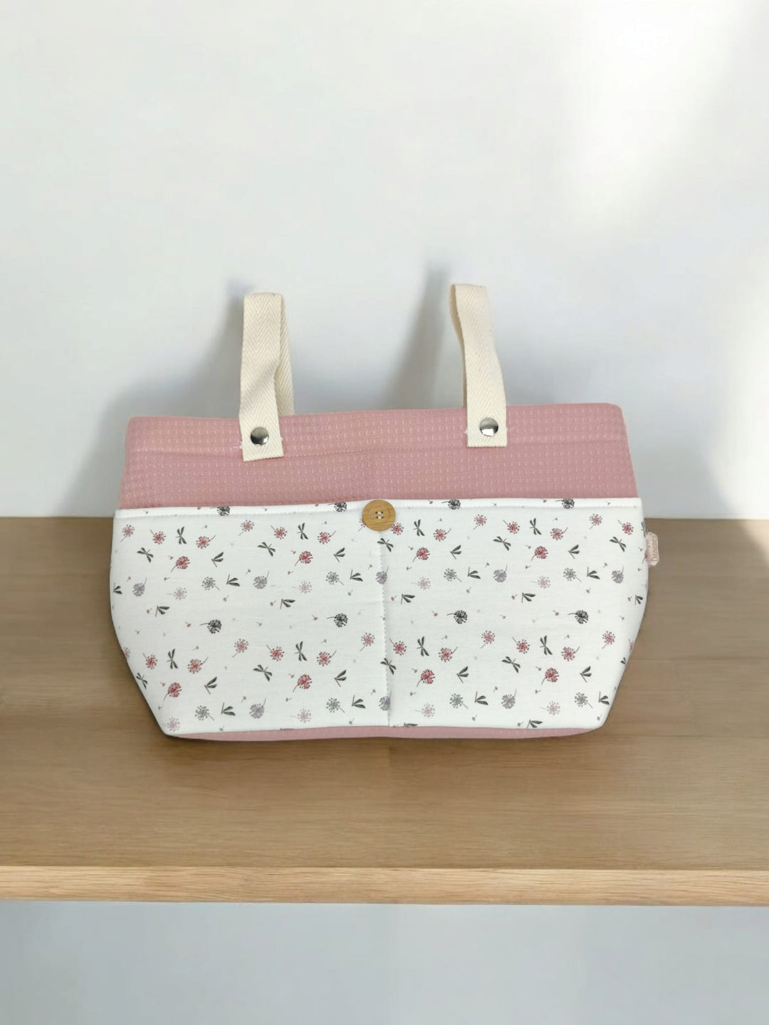 Bolso carrito rosa con base blanca y estampado de libélulas pequeñas, asas blancas y cierre dorado.