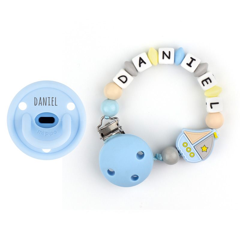 Chupete celeste personalizado con nombre y cadenita de silicona con letras y figura de barco color azul y amarillo.