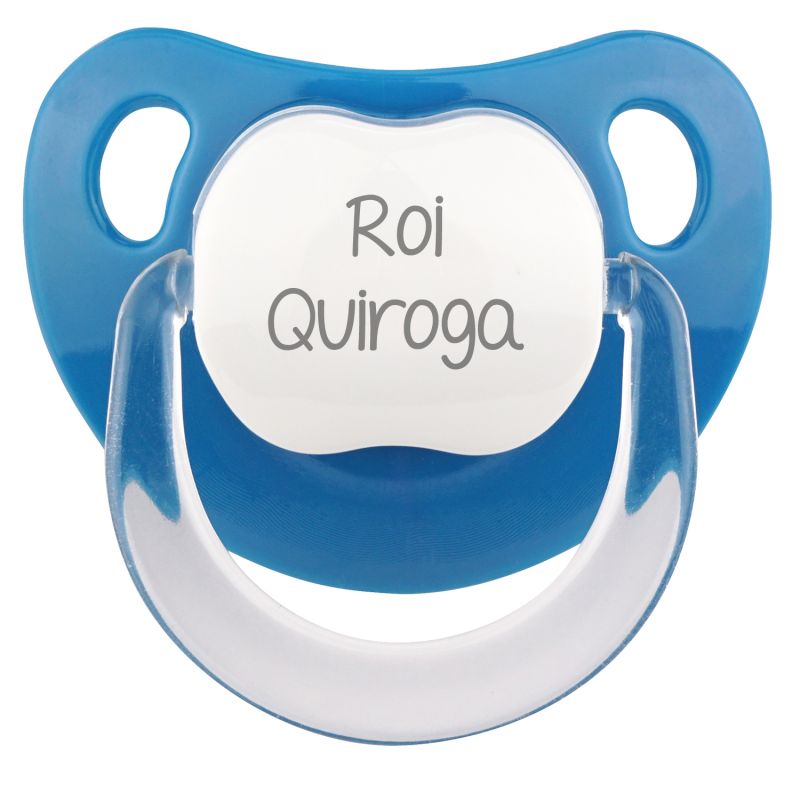 Chupete azul con tetina anatómica de látex transparente y escudo con nombre personalizado en blanco.