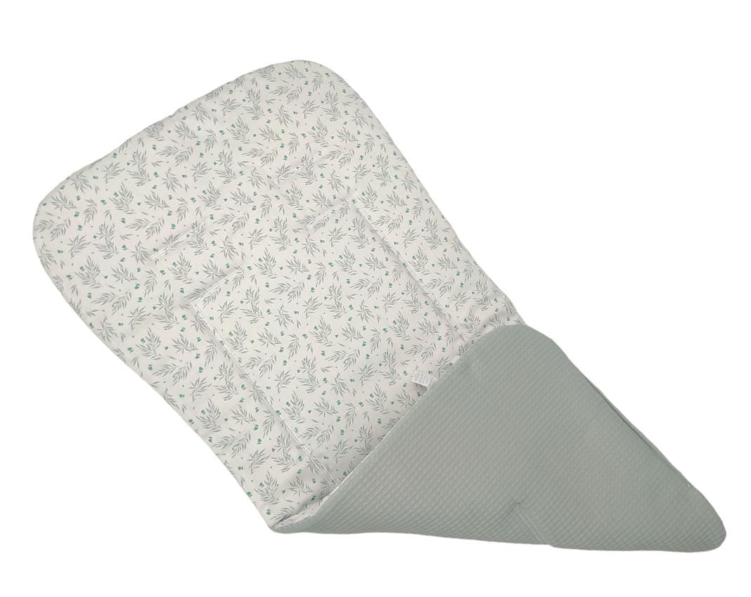 Colchoneta reversible con un lado de tela gris lisa y el otro con estampado de espigas en tonos verdes y mint, acolchonada y