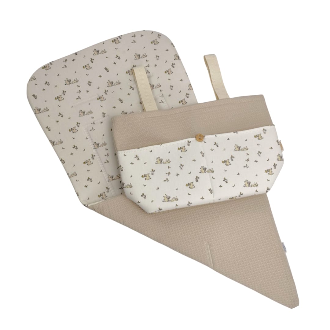 Colchoneta reversible beige con estampado de conejitos y bolso a juego con botón dorado.