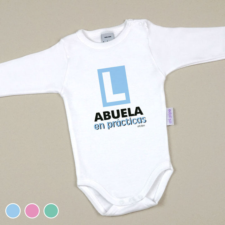 Body blanco de manga larga para bebé con letra L azul y texto "Abuela en prácticas" en negro y azul.