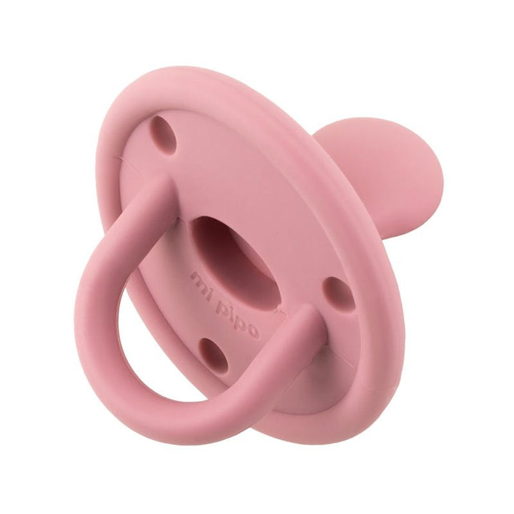 Chupete de silicona color rosa con forma redonda y aro para sujetar.